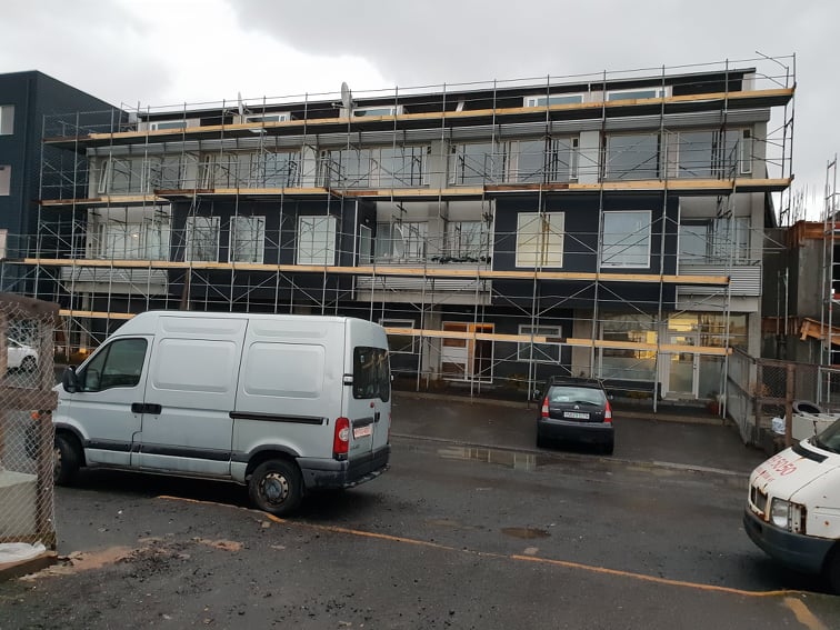 Vinnupallar meðfram langri byggingu með sendibíl fyrir framan.